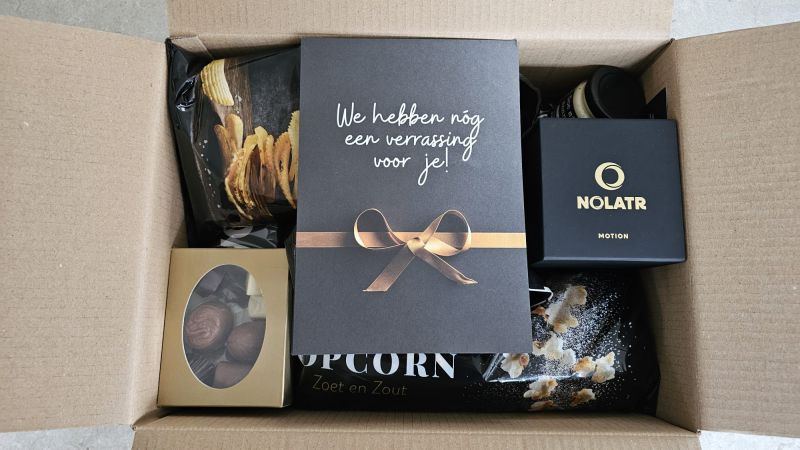 Het kerstpakket met een NOLATR-doos en een kaart: We hebben nog een verrassing voor je